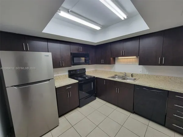 a kitchen with granite countertop a refrigerator sink stove and microwave