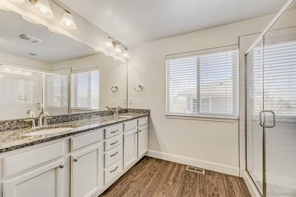 a bathroom with a granite countertop sink a mirror and a shower