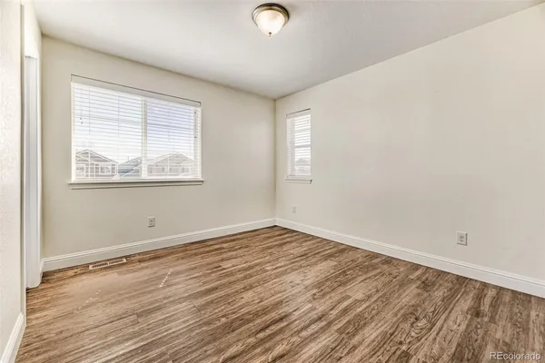 an empty room with wooden floor and windows