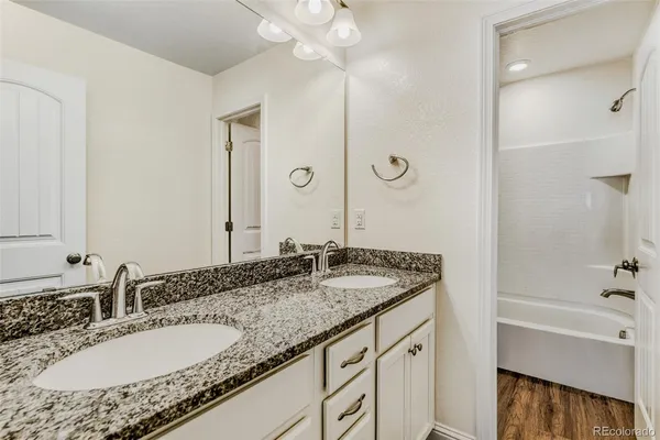 a bathroom with a granite countertop sink and a mirror a bathtub