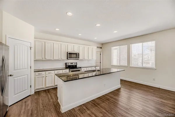 a kitchen with stainless steel appliances granite countertop a stove a sink and white cabinets