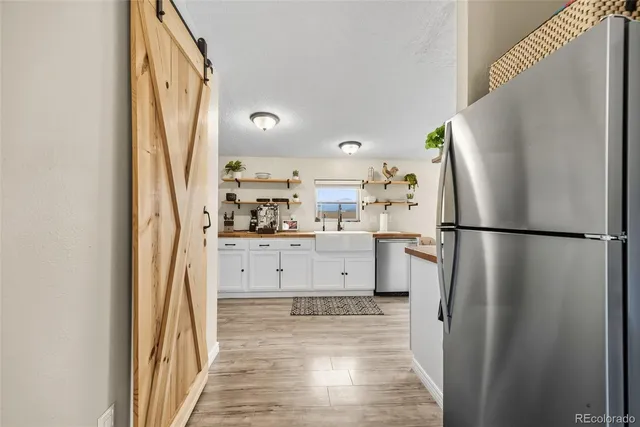 a kitchen with a refrigerator a sink and dishwasher with wooden floor