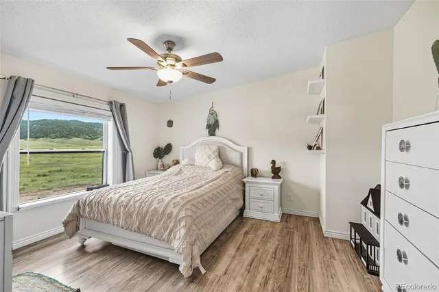 a bedroom with a bed and a large window with wooden floor