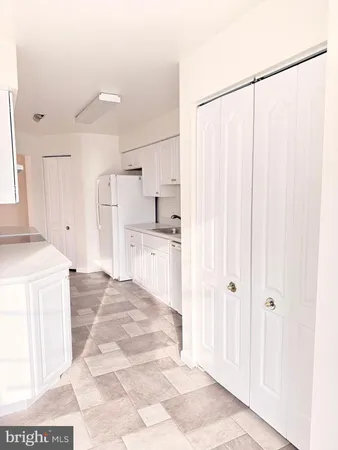 a large white kitchen with white cabinets and refrigerator