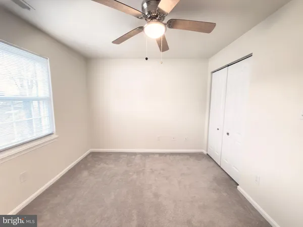 an empty room with a window and a fan