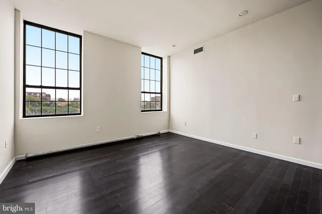an empty room with wooden floor and windows