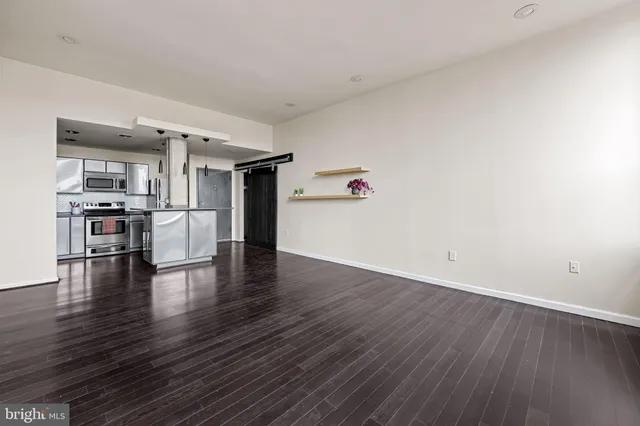 a view of empty room with kitchen and wooden floor