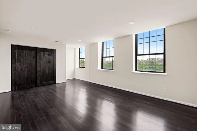 an empty room with wooden floor and windows