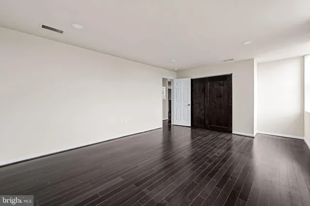 a view of an empty room with wooden floor and closet