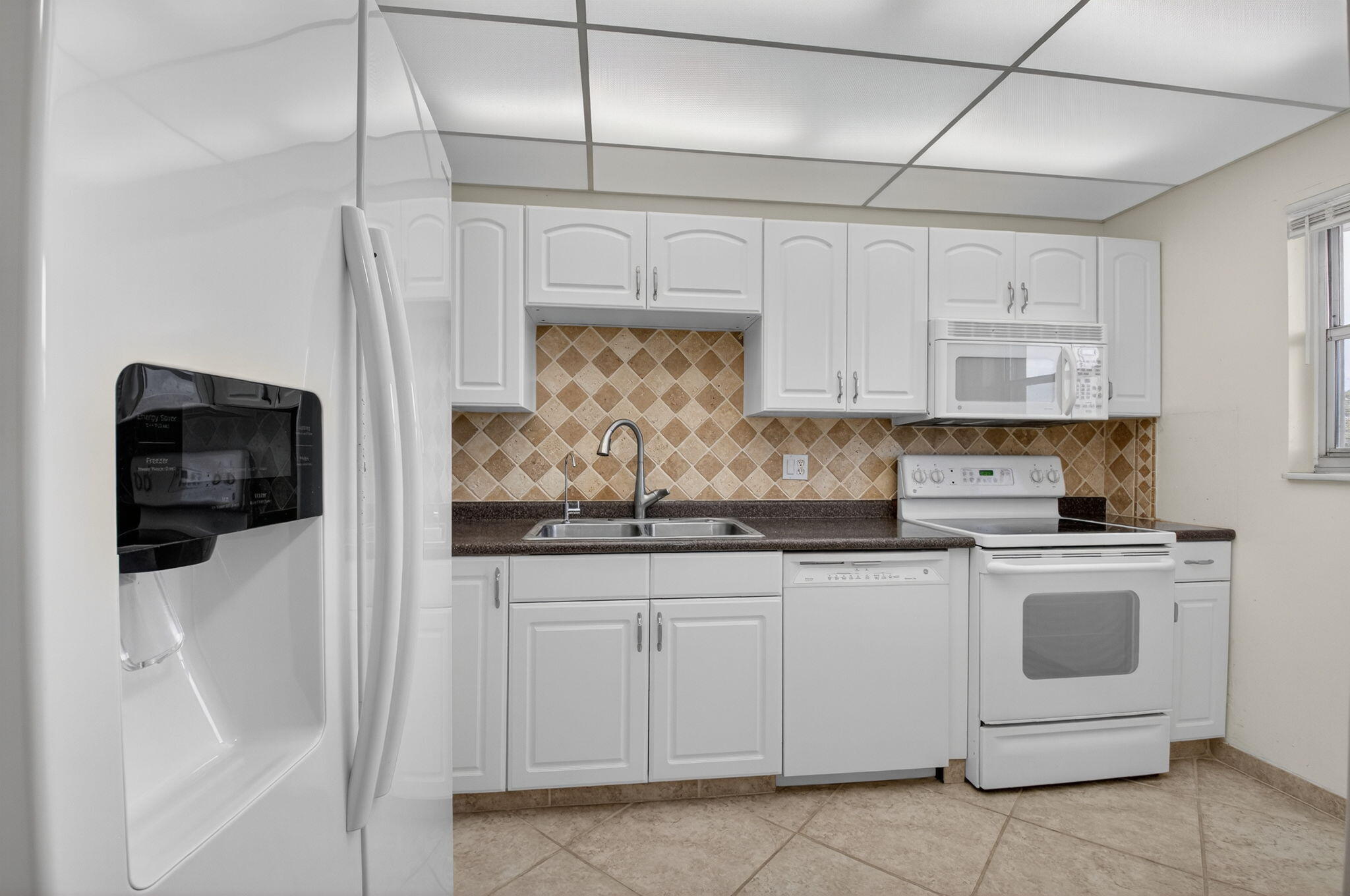 555 Northwest 4th Avenue, Unit 4230 Boca Raton, FL 33432 - Photo 11 of 38 a kitchen with white cabinets and white appliances