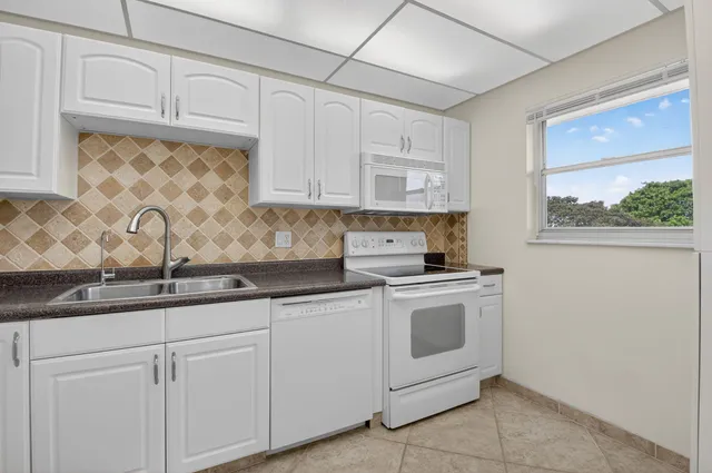 a kitchen with granite countertop white cabinets and white appliances