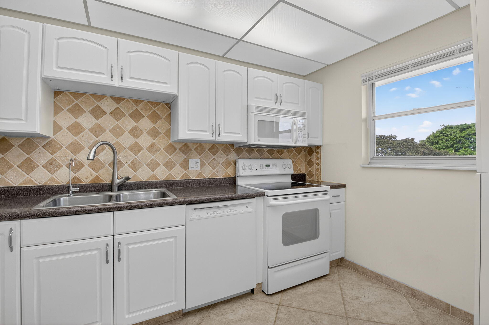 555 Northwest 4th Avenue, Unit 4230 Boca Raton, FL 33432 - Photo 12 of 38 a kitchen with granite countertop white cabinets and white appliances