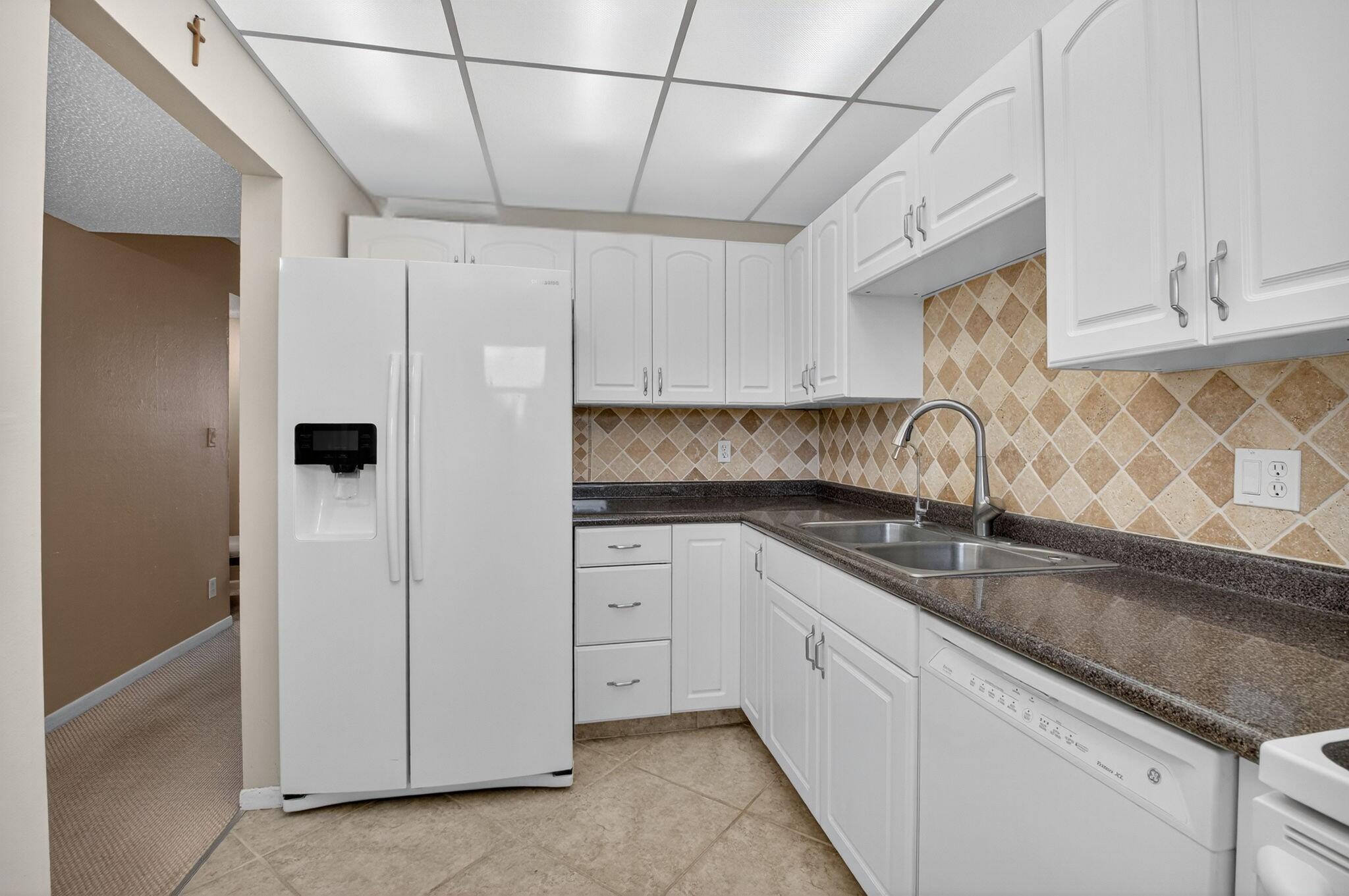555 Northwest 4th Avenue, Unit 4230 Boca Raton, FL 33432 - Photo 13 of 38 a kitchen with granite countertop white cabinets and refrigerator