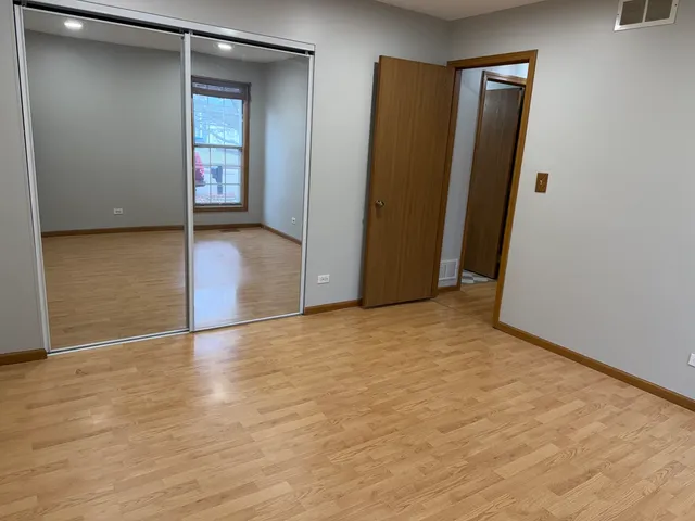 a view of an empty room with closet and wooden floor