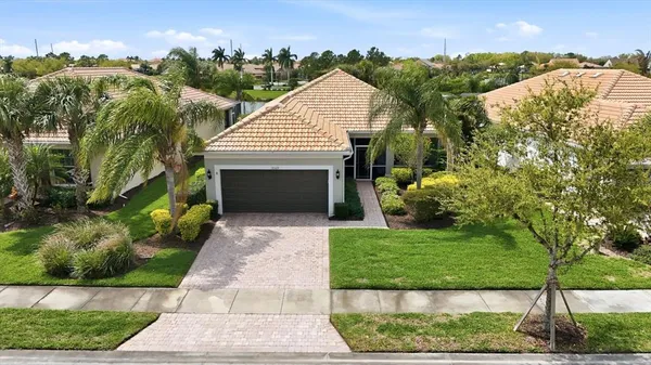 a front view of a house with a garden and palm trees