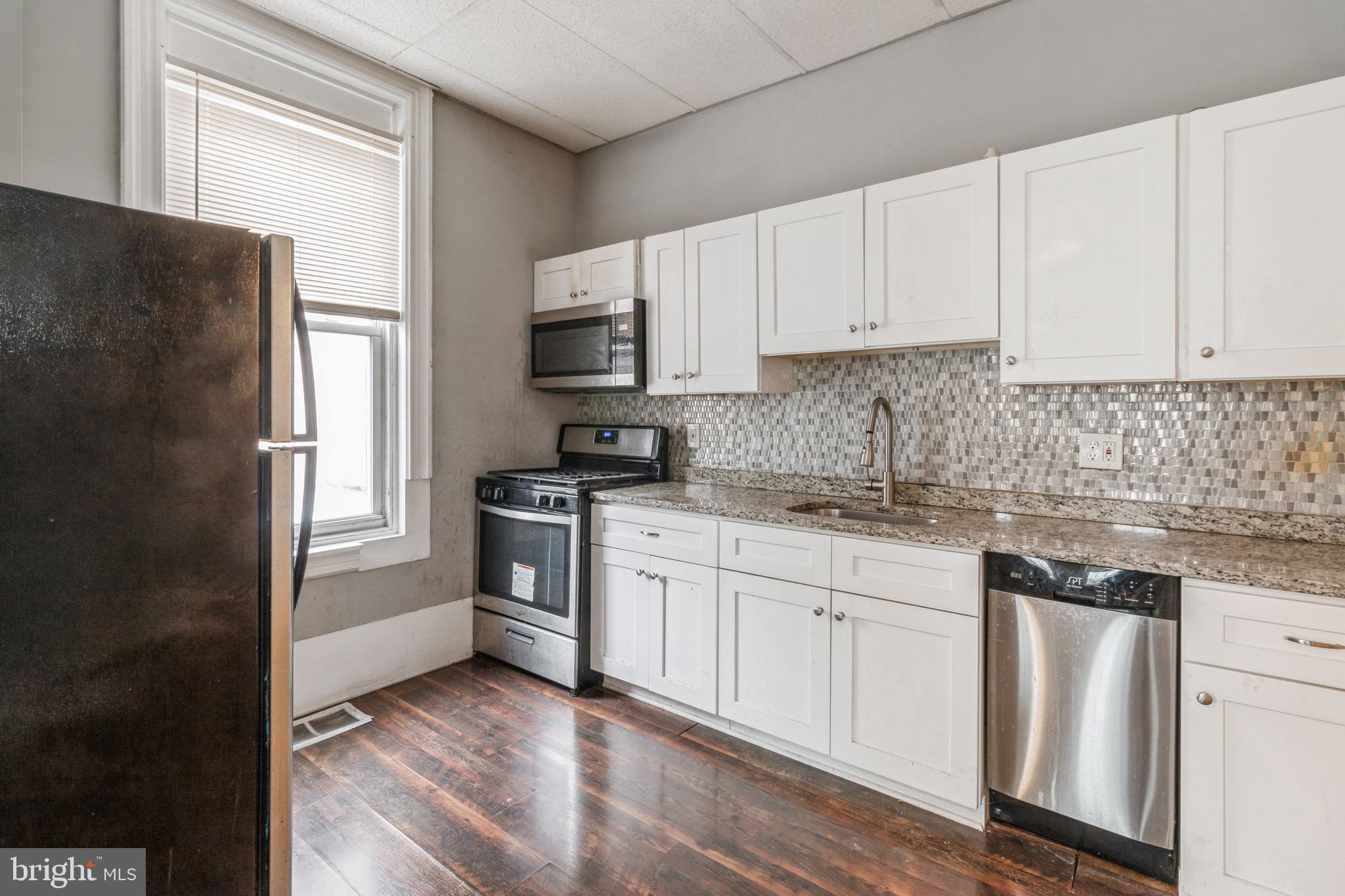 525-527 Penn Street, Unit 1A Camden, NJ 08102 - Photo 4 of 12 a kitchen with granite countertop white cabinets and white appliances