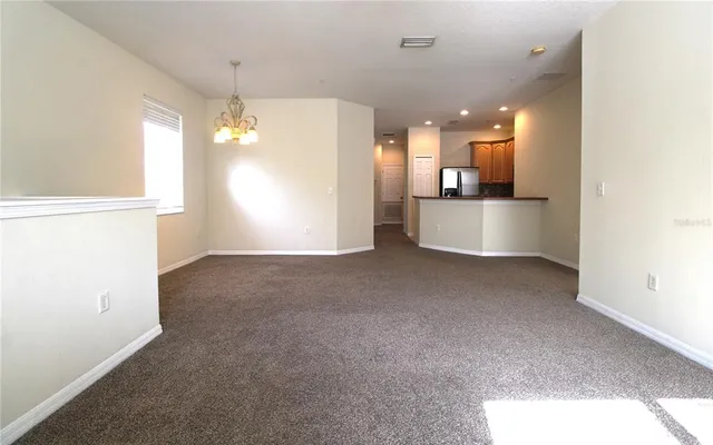 a view of a hallway with kitchen and chandelier