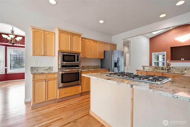 a kitchen with stainless steel appliances granite countertop a stove a sink and a refrigerator