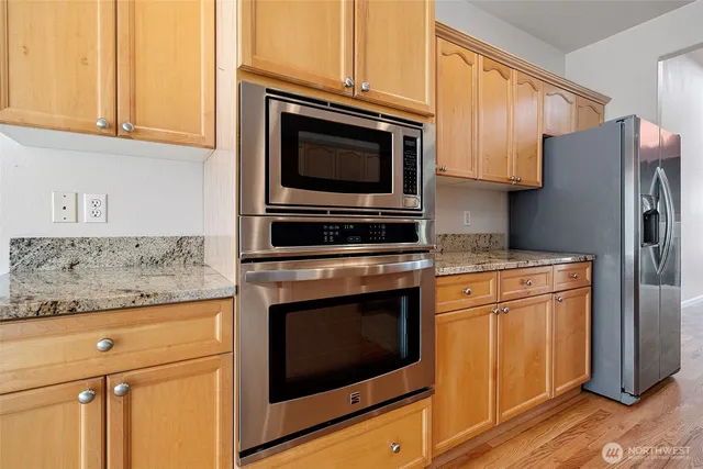 a kitchen with granite countertop wooden cabinets stainless steel appliances and a counter space