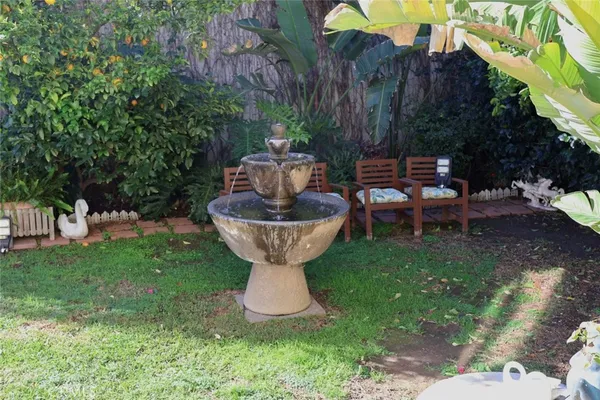 a view of a backyard with table and chairs potted plants and a fountain