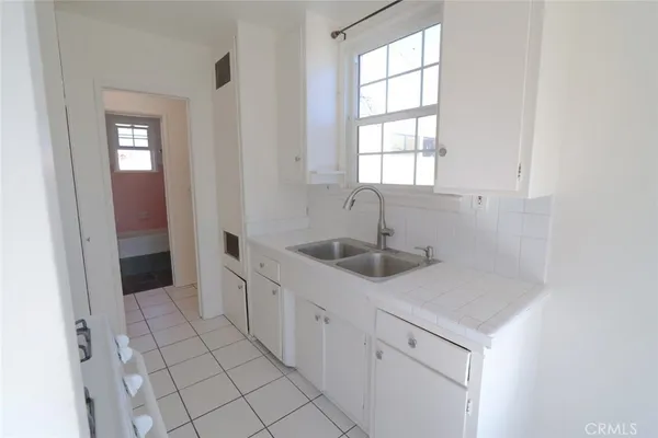 a kitchen with white cabinets a sink and a window