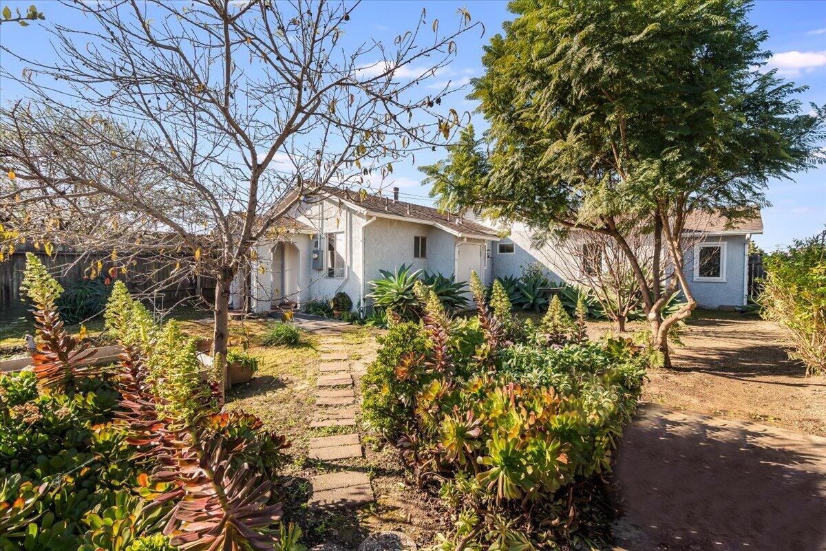 230 North D Street Lompoc, CA 93436 - Photo 24 of 29 a yellow house with flower garden in front of it