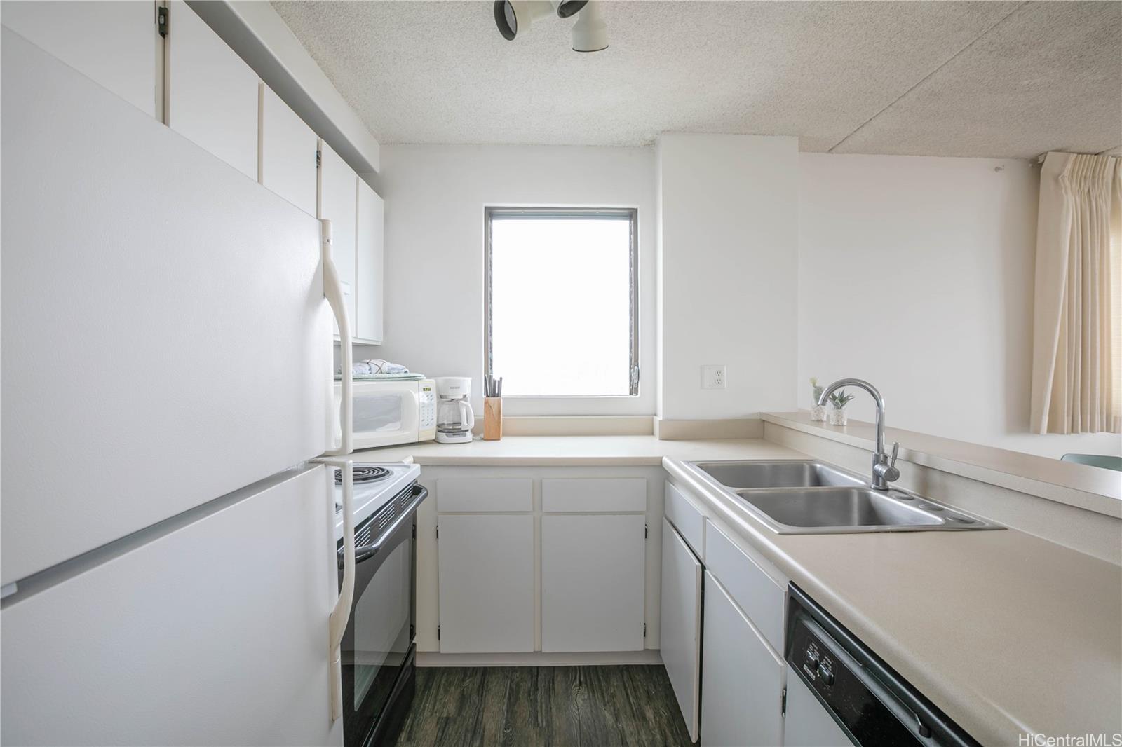 2240 Kūhiō Avenue, Unit 2608 Honolulu, HI 96815 - Photo 7 of 25 a kitchen with a sink cabinets stainless steel appliances and a window