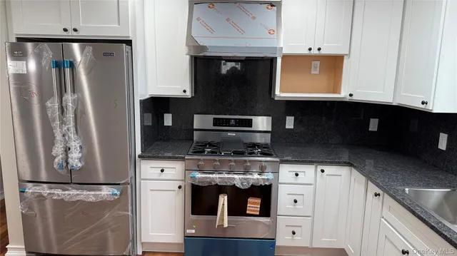 a kitchen with stainless steel appliances granite countertop a stove a refrigerator and a microwave