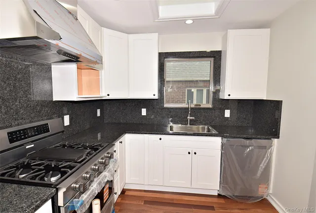 a kitchen with granite countertop a sink stove and cabinets