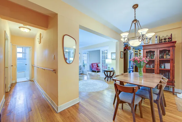 a dining room with wooden floor a chandelier a wooden table and chairs