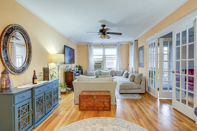 a living room with furniture a mirror and a wooden floor