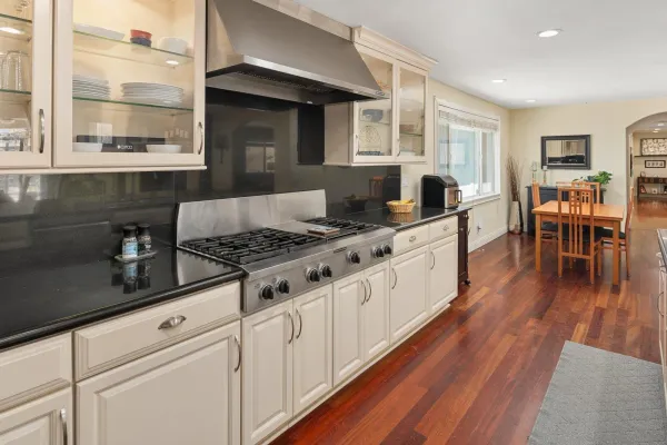 a kitchen with granite countertop a stove a sink a dining table and chairs