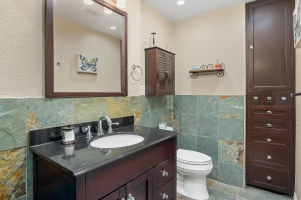 a bathroom with a granite countertop sink toilet and mirror