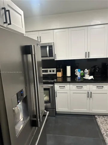 a kitchen with stainless steel appliances kitchen island granite countertop a refrigerator and a stove top oven