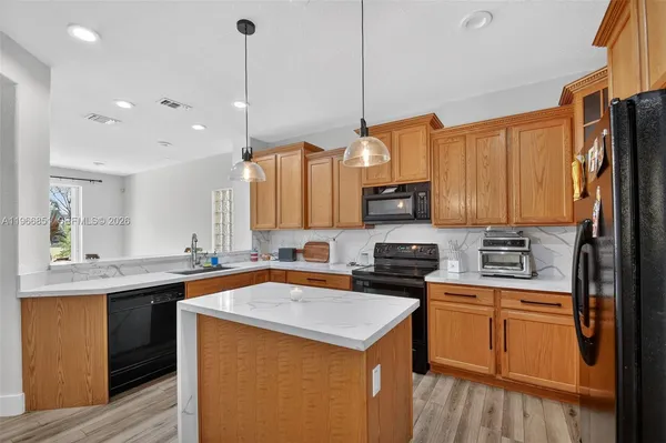 a kitchen with stainless steel appliances granite countertop a sink a stove and a wooden floors