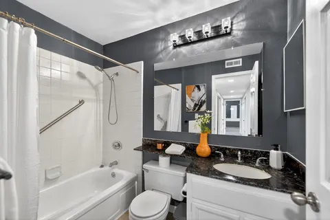 a bathroom with a granite countertop tub sink and mirror