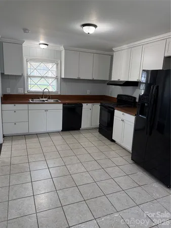 a large kitchen with a stove a sink a microwave and cabinets