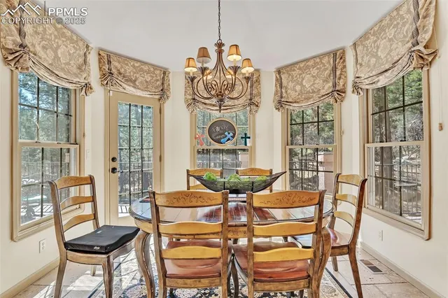a dining room with wooden floor a chandelier a glass table and chairs
