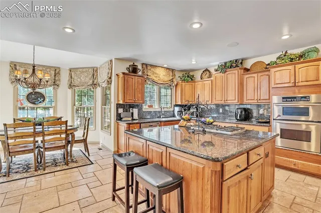 a kitchen with stainless steel appliances granite countertop a stove a sink dishwasher and a refrigerator with wooden cabinets