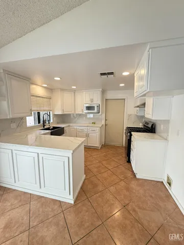 a kitchen with granite countertop white cabinets and stainless steel appliances