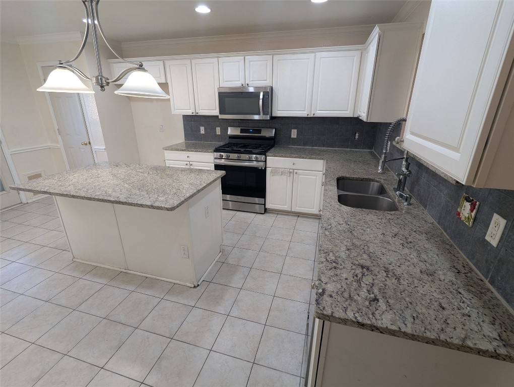 1016 Stacia's Way Pflugerville, TX 78660 - Photo 5 of 34 Kitchen with granite counters decorative backsplash, stainless steel appliances, island, white cabinetry, and pendant lighting
