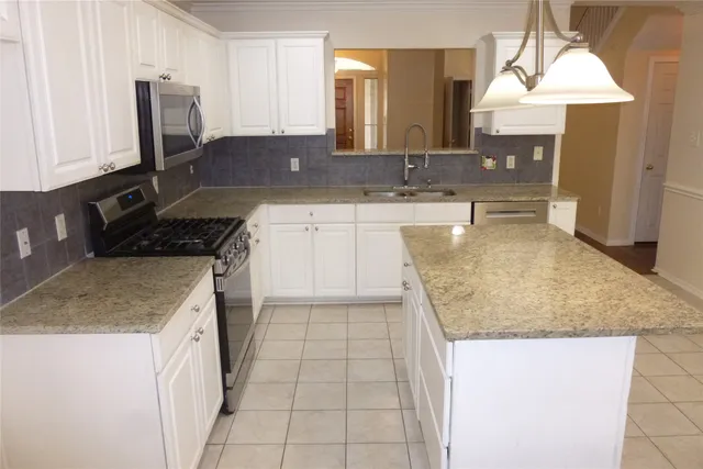 a kitchen with a granite countertop sink and cabinets