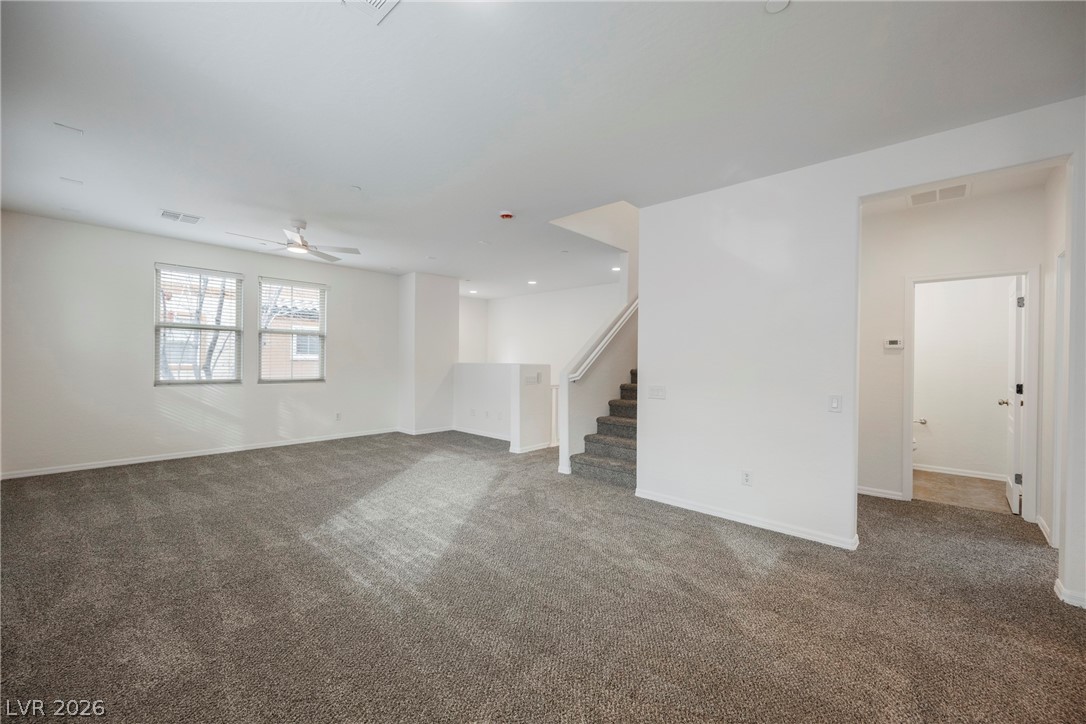 4650 Ranch House Road, Unit 64 North Las Vegas, NV 89031 - Photo 18 of 39 This generous living room features plush carpeting and multiple windows, creating a welcoming and comfortable space.
