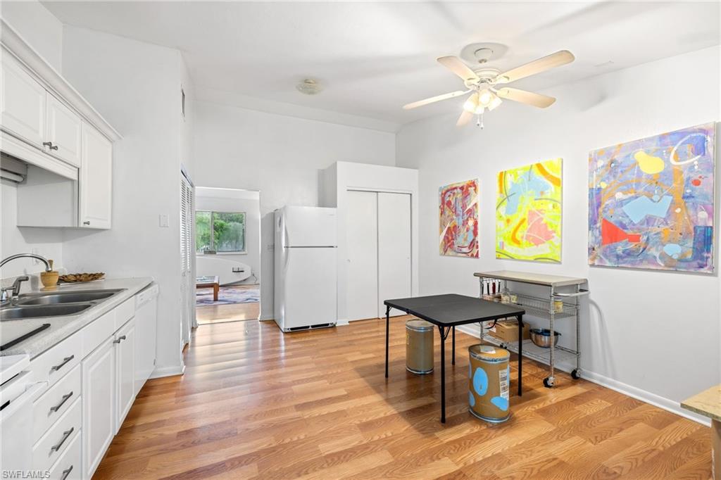 5406 16th Place Southwest, Unit E4 Naples, FL 34116 - Photo 11 of 26 a kitchen with stainless steel appliances kitchen island granite countertop a table chairs in it and wooden floors