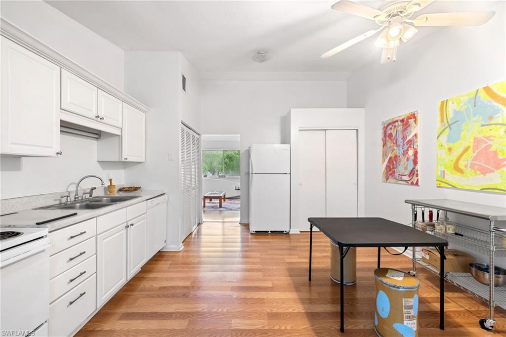 5406 16th Place Southwest, Unit E4 Naples, FL 34116 - Photo 12 of 26 a kitchen with stainless steel appliances granite countertop a stove top oven a sink a dining table and chairs with white cabinets