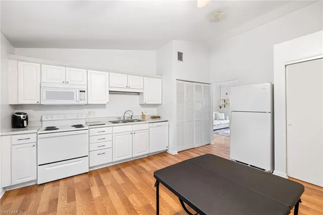 a kitchen with granite countertop a refrigerator sink stove and white cabinets