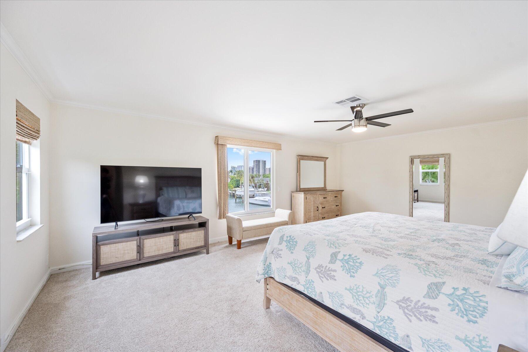 1180 Singer Drive Singer Island, FL 33404 - Photo 18 of 24 a spacious bedroom with a bed and a flat screen tv