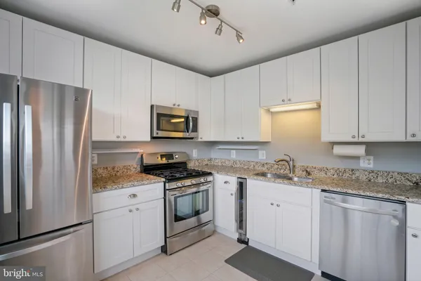 a kitchen with stainless steel appliances granite countertop white cabinets granite counter tops and a stove