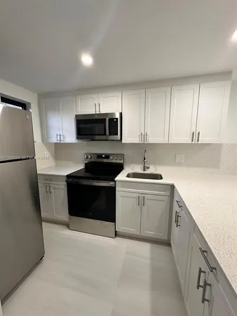 a kitchen with granite countertop a refrigerator and a stove top oven