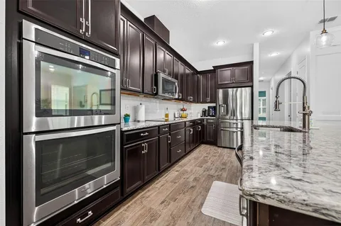 a kitchen with stainless steel appliances granite countertop a refrigerator a stove and a sink
